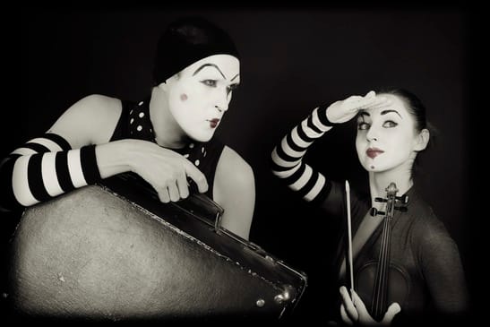 mimes woman and man with suitcase and violin